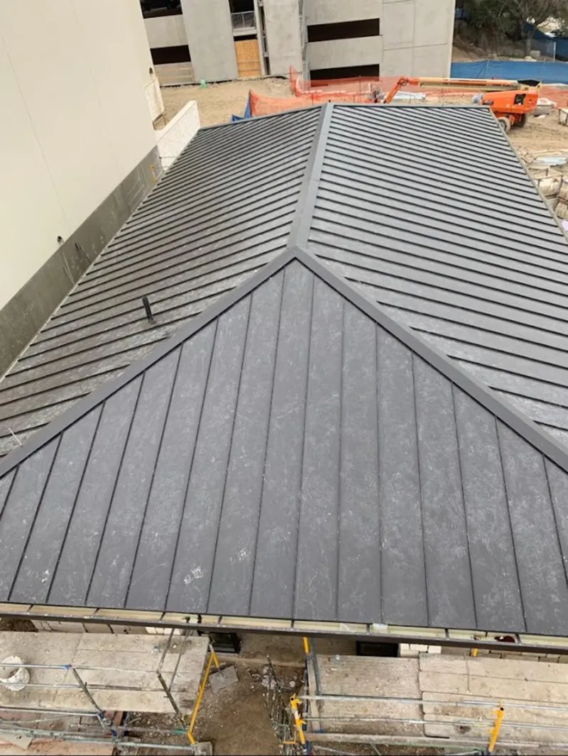 Commercial metal roof construction with crane equipment in Manvel